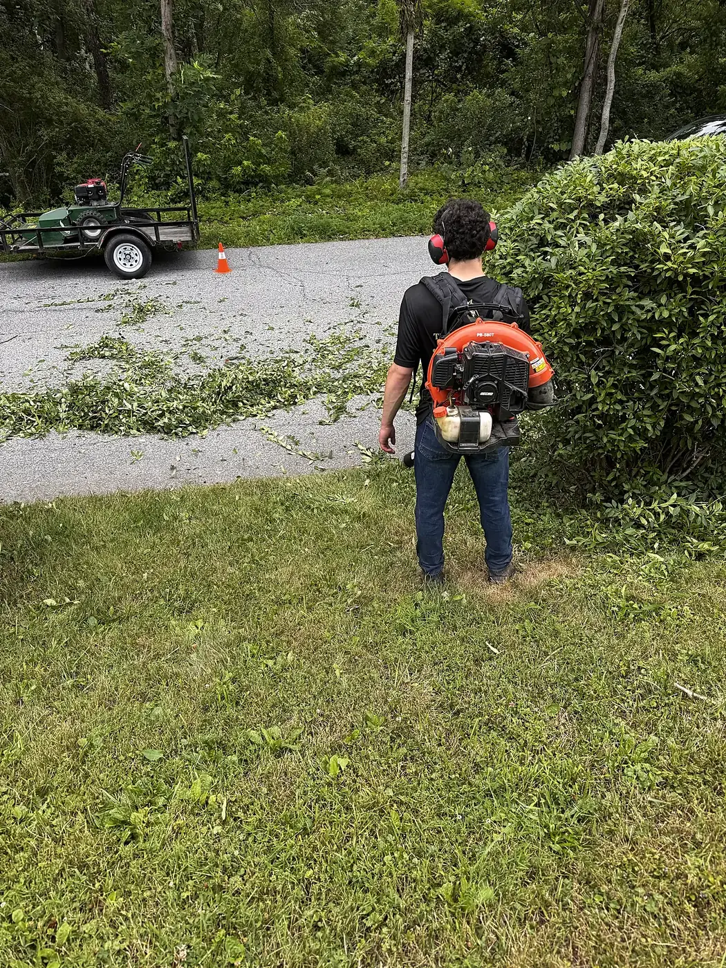 Crew member with a backpack blower cleaning up a driveway after trimming