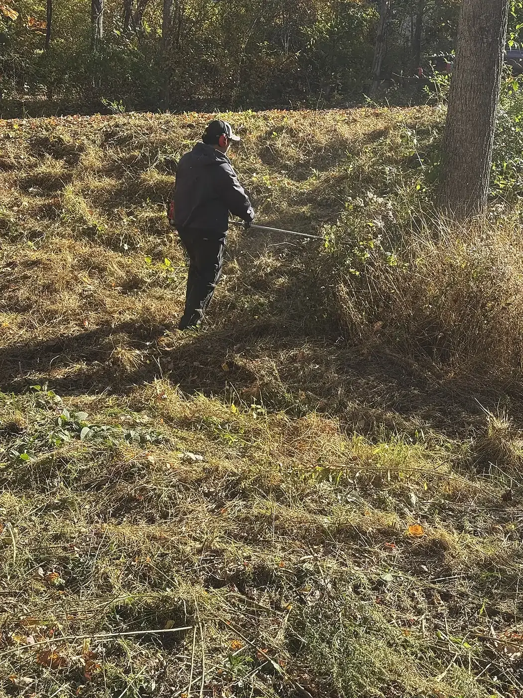 Crew member with a brush cutter finishing a slope